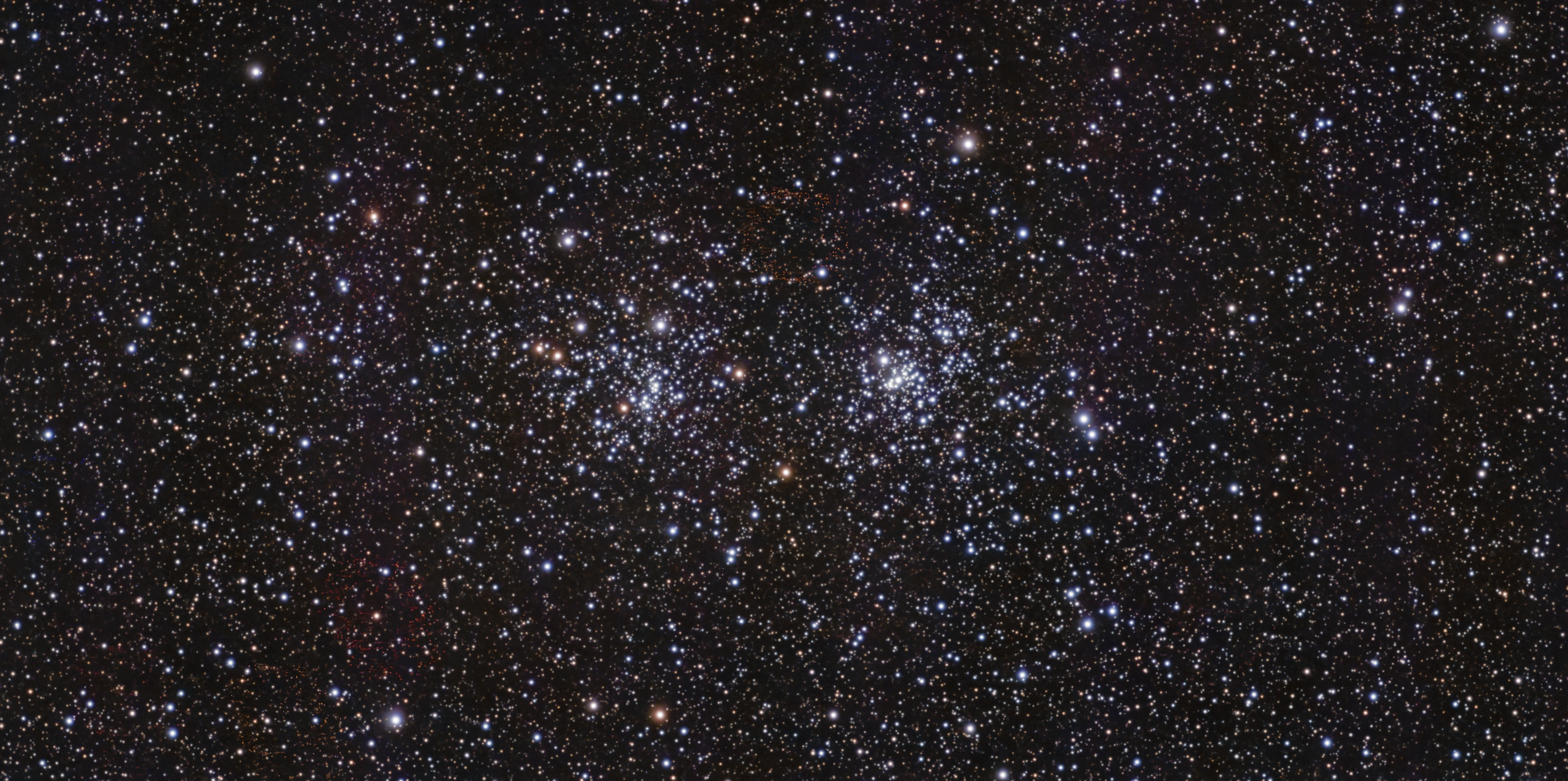 Two dense clusters of blue-white and golden stars in a wide star field in Perseus
